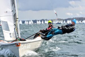 Dwóch żeglarzy na trapezie podczas regat pod żaglami Ocean Sails